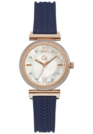 Orologio ovale in rosé con quadrante in madreperla, sei indicatori in diamante, cinturino in gomma blu e una trama a spina di pesce testurizzata.