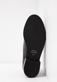 Semelle de chaussure en cuir noir à texture lisse, marquée "JONAK Paris Made in Portugal" et taille 37, présentant un bout arrondi et un léger talon.