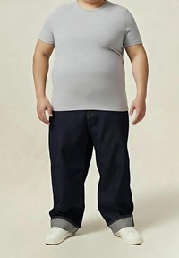 Szara koszulka z krótkim rękawem, luźne granatowe dżinsy z podwiniętymi nogawkami oraz białe wsuwane buty. Prosty, casualowy strój.