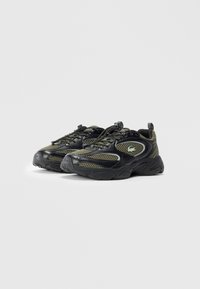 Black and olive green mesh sports shoes with thick soles, lace sliders, and a crocodile logo on the side, positioned side by side.