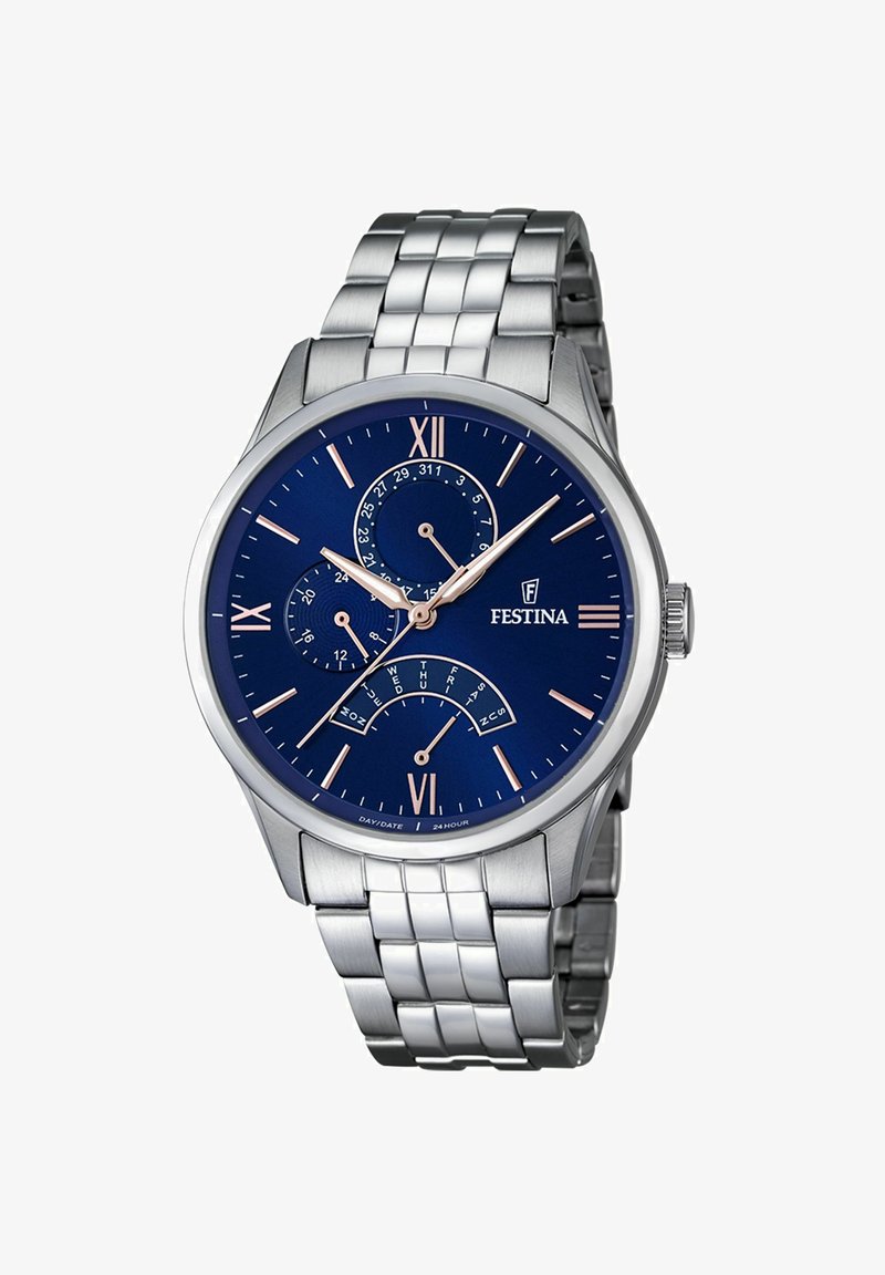 Sudraba metāla rokas pulkstenis ar zilu ciparnīcu, romiešu cipariem un trim subciparnīcām. Iekļauj saistītu rokassprādzi un pulētu akcentu.