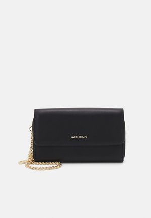 Borsa in pelle nera con tracolla in catena dorata, pattina pieghevole e logo "VALENTINO" impresso. Dettaglio con zip lungo il lato. Compatta e rettangolare.