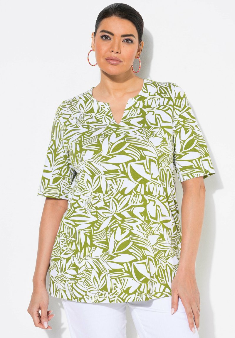 Blusa de estampado verde y blanco con mangas cortas, diseño de cuello en V, que presenta un print de hojas sobre una tela suave. Combinada con pantalones blancos.