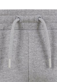 Pelēki sporta bikses ar aukliņu aizdari un pelēkiem caurumiņiem, izgatavotas no mīkstas auduma ar gludu tekstūru.