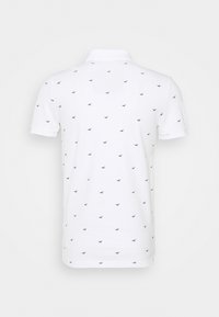 Polo blanc à manches courtes avec petits motifs noirs de mouettes uniformément espacés, montré de dos sur un fond uni.