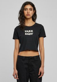 Svart kortermet t-skjorte laget av bomull med "TAKE IT EASY" trykt med fet skrift. Korte ermer og rund hals med et enkelt design.