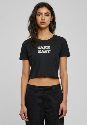 Black cropped t-shirt made of cotton featuring "TAKE IT EASY" printed in bold letters. Short sleeves and round neckline with a simple design.