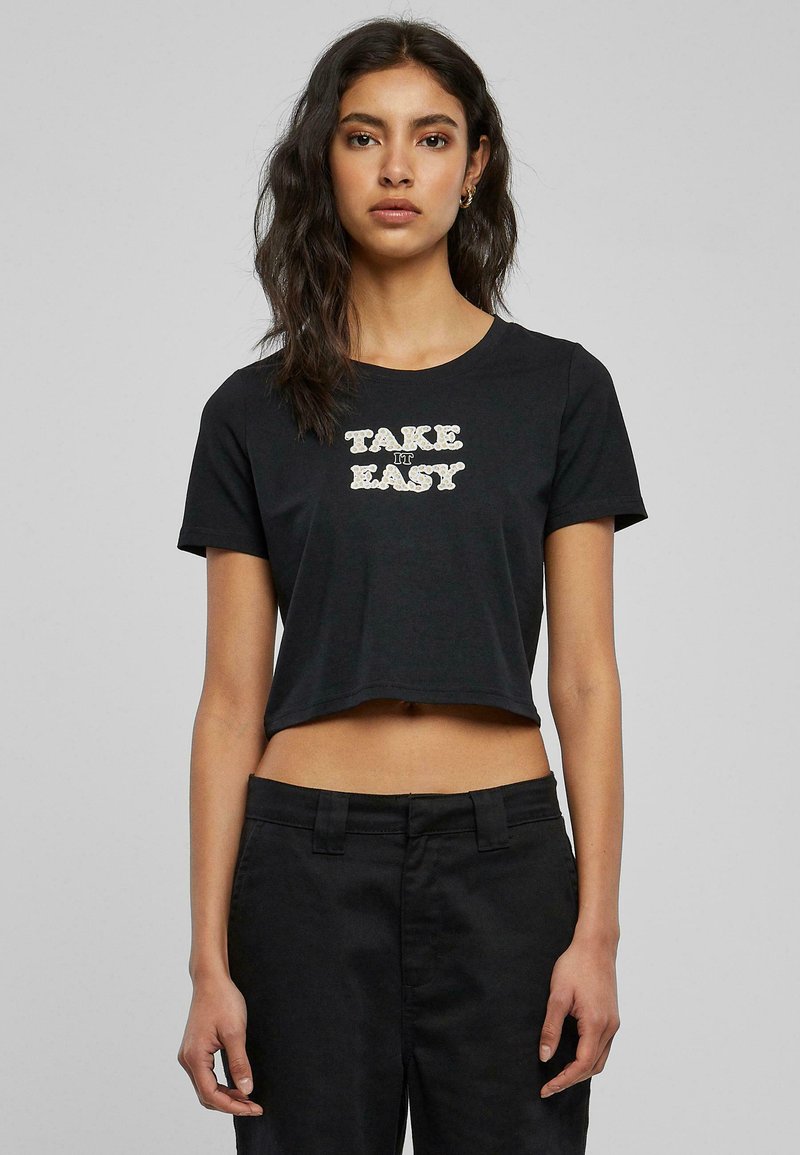 Svart kortermet t-skjorte laget av bomull med "TAKE IT EASY" trykt med fet skrift. Korte ermer og rund hals med et enkelt design.