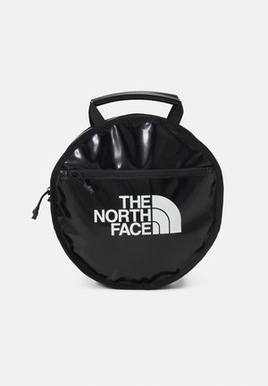 Okrągła czarna torba na zamek z górnym uchwytem i białym logo "THE NORTH FACE" na przedniej kieszeni.