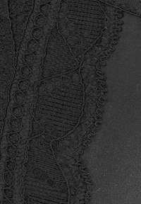 Tessuto nero con maglia testurizzata e dettagli in pizzo. La superficie liscia affiancata a motivi complessi crea contrasto visivo e profondità.