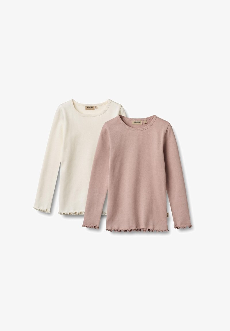 Deux chemises en tricot côtelé à manches longues pour enfants, une rose pâle et une blanc cassé, avec des bords froncés aux manches et aux ourlets.