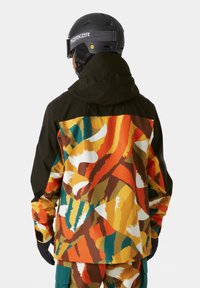 Bunte Skijacke mit einer Mischung aus orangefarbenen, gelben, grünen und braunen abstrakten Mustern; verfügt über eine schwarze Kapuze und Besätze sowie eine strapazierfähige Textur.