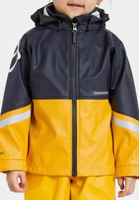 Gul och marinblå vattentät jacka med dragkedja, reflexstripes och huva. "Didriksons"-logotyp på bröstet. Slät textur.