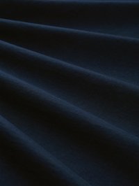 Σκούρο ναυτικό μπλε ύφασμα με απαλές, διαγώνιες πτυχώσεις που δημιουργούν απαλά σκιές και φωτισμούς στην επιφάνεια.