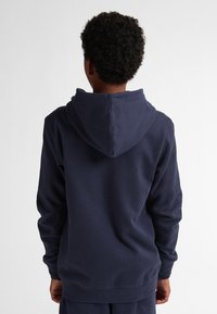 Sudadera azul marino con un bolsillo canguro, capucha con cordón, puños y dobladillo de canalé. La suave tela de algodón proporciona un ajuste cómodo.