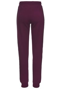 Lila Jogginghose aus weichem Stoff mit elastischem Bund, schmal zulaufenden Beinen und gerippten Bündchen. Das Design verfügt über schwarze Einsätze an den Seiten.