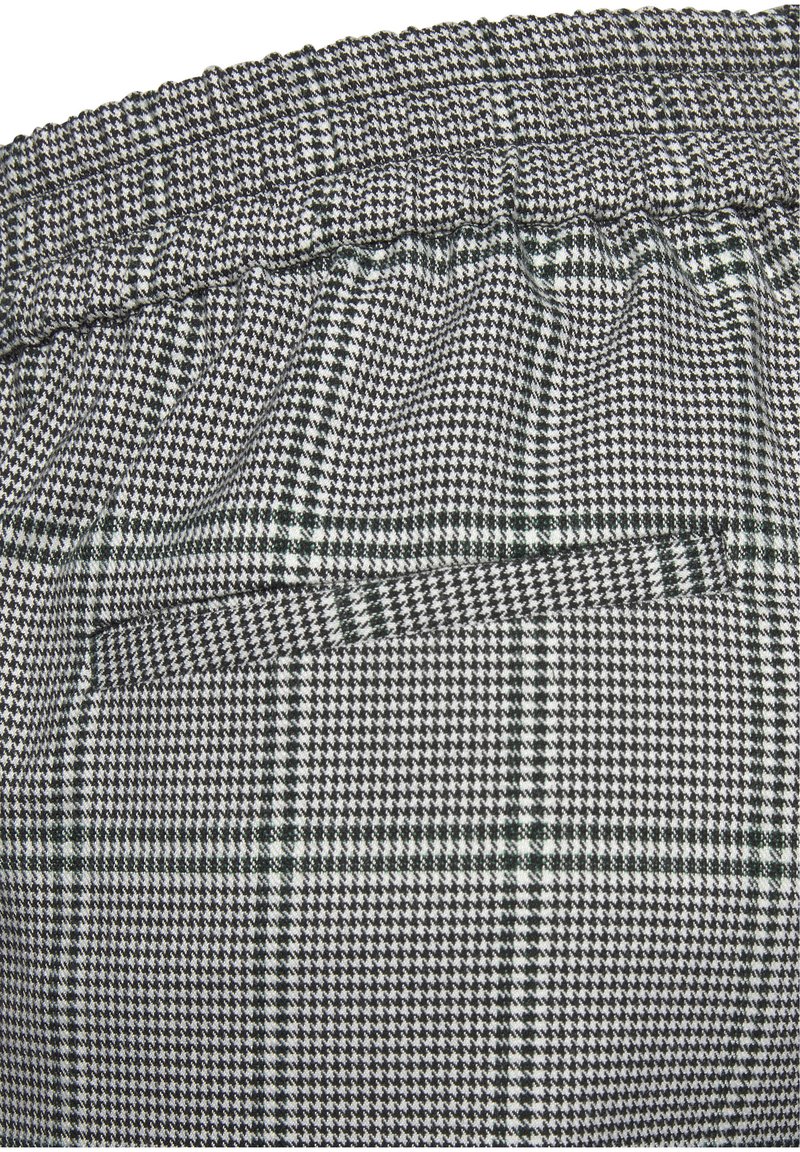 Grijs-wit geblokt stof met groene accenten, met een elastische tailleband en een achterzakdetail. Getextureerd geweven patroon.