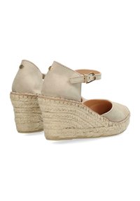 Beige suede wedge shoes with an ankle strap, featuring a braided jute platform and round toe design, smooth texture, and gold hardware accents.
