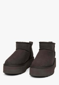 Donkergrijze suède enkelboots met een ronde neus, een zachte textuur en een dikke platformzool. Voorzien van stikdetails langs de naden.