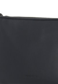 Borsa a pochette in pelle nera con una superficie liscia, chiusura con cerniera superiore e logo impresso sul fronte. Design rettangolare compatto.