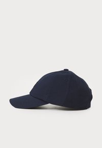 Marineblå baseballcaps med buet skjerm, sydd detaljer, ventilasjonsåpninger og justerbar bakrem. Klassisk bomullsmateriale.