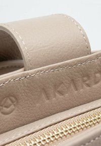 Borsa a mano in pelle beige con finitura testurizzata, dotata di una zip dorata e logo impresso, completata da dettagli di cucitura intricati.