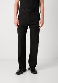 Black straight-leg trousers made from fabric with a smooth texture. Features a button closure, side pockets, and a classic design.
