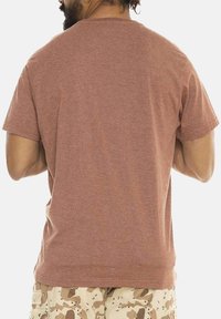 T-shirt marron à manches courtes avec un col rond, fabriqué en mélange de coton doux, présentant une texture lisse et une coupe décontractée.