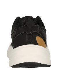 Musta urheilukenkä, jossa on teksturoitu verkkopinta, vahvistettu kanta ja valkoinen kumipohja. Sivussa on ruskea yksityiskohta.