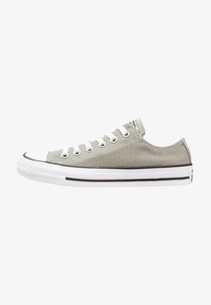 Canvas sneakers in light grey with white rubber sole, classic rounded toe, and five eyelet lacing. Black stripe accents along the sole.