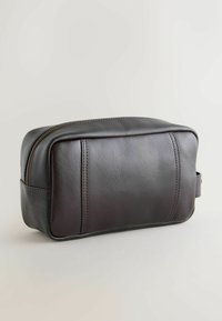 Pungă neagră din piele, de formă dreptunghiulară, cu închidere cu fermoar și detalii subtile de cusături pe suprafață, având o mânere laterală.