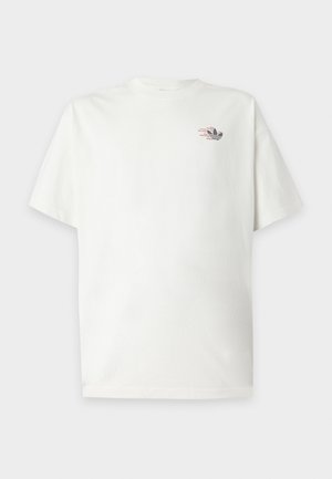 T-shirt blanc à manches courtes avec un petit logo Adidas noir et rouge sur la partie supérieure gauche de la poitrine.