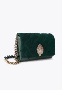 Borsa a tracolla in suede verde trapuntato con una catena dorata, dotata di una chiusura decorativa con embellishments. Forma rettangolare compatta.