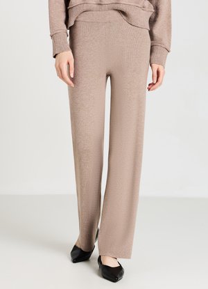 Pantaloni beige a maglia con design a gamba larga e una texture liscia, abbinati a scarpe basse nere a punta. Stile casual e semplice.