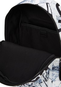 Interior de la mochila con un forro de tela negra, un compartimento amplio y un pequeño bolsillo lateral. El exterior presenta un diseño abstracto en blanco y azul.