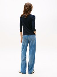 Marineblå slim-fit topp med trekvartlange ermer, kombinert med høytlivs lys blå vide jeans, med en klassisk denimtekstur.
