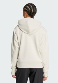 Cream-colored hooded sweatshirt with a relaxed fit, ribbed cuffs, and hem. Features a smooth texture and subtle stitching details.
