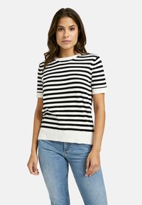 Black and white striped short-sleeve sweater with a crew neckline and ribbed hem, worn with light blue jeans.