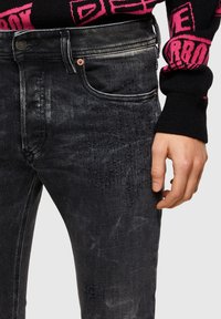 Vaqueros negros de denim desgastado con un corte ajustado, que presentan un sutil efecto desteñido, diseño de cinco bolsillos y cierre con botón metálico.