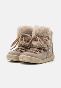 Bottes en suède beige avec bordure en fausse fourrure, dotées de lacets marron et de motifs en étoile en argent et or. Semelles en caoutchouc avec texture striée.