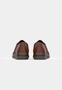 Chaussures en cuir marron avec une finition lisse, une forme arrondie et un petit talon. Présentent des coutures minimales et une semelle en caoutchouc texturée pour une meilleure adhérence.
