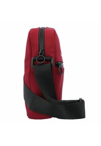 Borsa a tracolla rossa in tessuto con una texture liscia, tracolla nera regolabile, due scomparti con zip e bordi arrotondati.