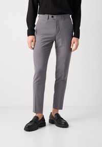 Gray tailored pants with a slim fit, made from smooth fabric. Features a flat front, side pockets, and a button closure. Worn with black loafers.