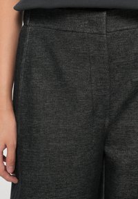 Grå teksturert stoff cropped bukser med flat midje og side søm detaljer, som viser et glatt, elastisk materiale.