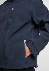 Tamsiai mėlyna striukė su užtrauktuku priekyje, šoniniais kišenėmis ir lygiu audiniu. Sukurta su gobtuvu ir reguliuojamais rankogaliais, kad būtų užtikrintas patogus prigludimas.