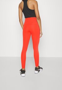 Czerwone legginsy wysokie w talii o dopasowanym kroju, wykonane z elastycznego materiału. Posiadają bezszwowy wygląd i subtelną markę w okolicy kostki.