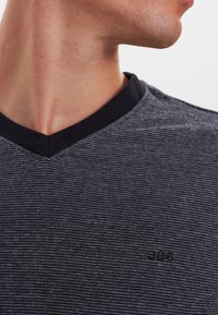 Gråstribet V-neck t-shirt med sort halsudskæring. Har et lille sort logo nær kraven. Stoffet ser glat og let ud.