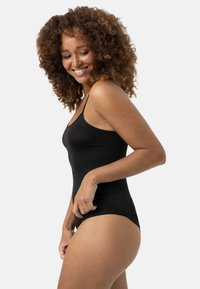 Sort tank bodysuit med tynde stropper, glat tekstur og tætsiddende design, der viser en sideprofil mod en ensfarvet baggrund.