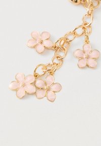 Kullatooni ketiga käevõru, millel on neli roosast emailist lille, millel on peened detailid ja kuldsed servad, luues õrna lillemustriga disaini.