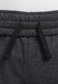 Grijze sweatpants hebben een elastische tailleband met een zwarte trekkoord. De textuur is zacht, met een subtiel heatherpatroon erdoorheen.